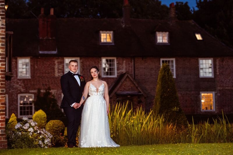 A couple stand in the grounds of Solton Manor in front of the historic house after getting married