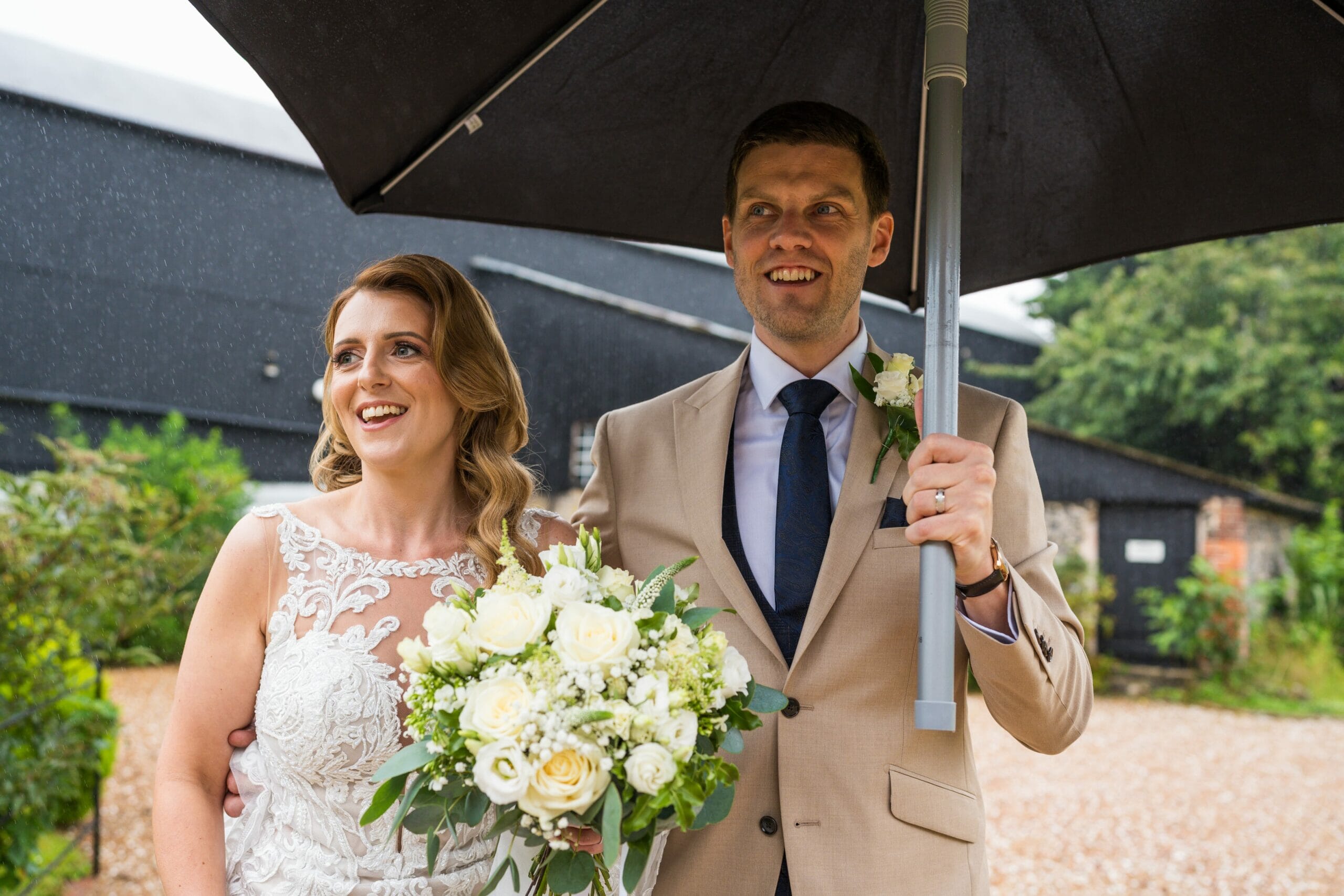 A couple hold an umbrella, during a wedding at Solton Manor, near Deal