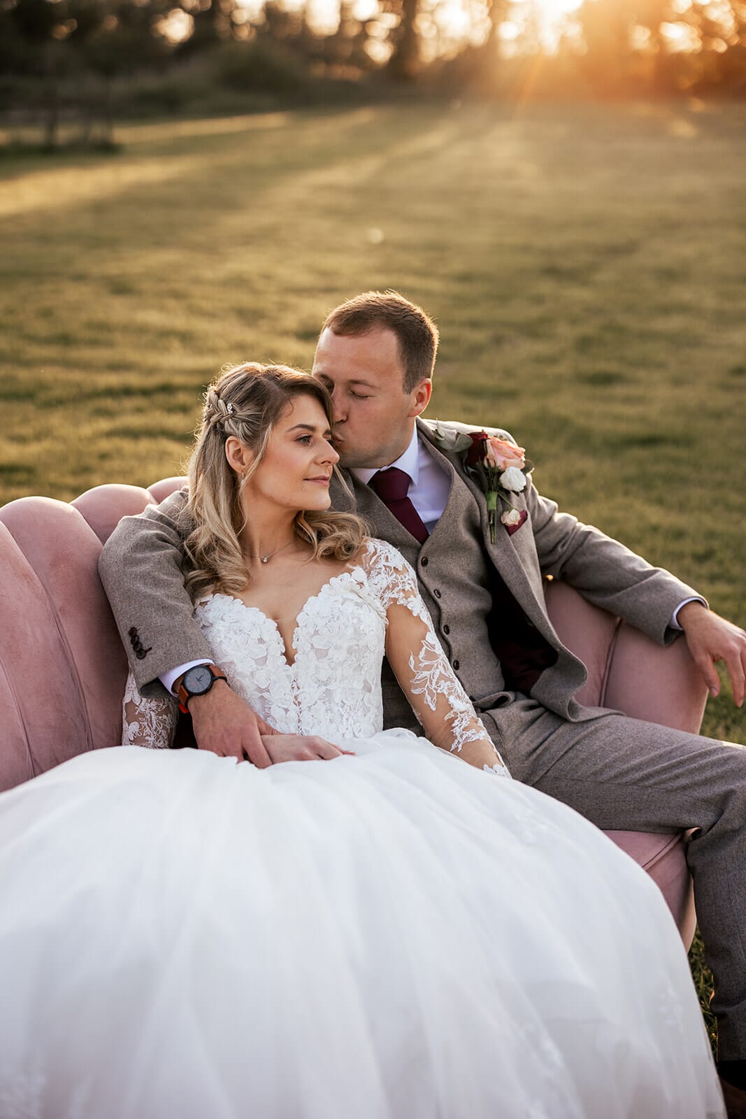 A bride and groom enjoy golden hour on a sofa in the Famine Downs Meadow at Solton Manor, near Kingsdown, Walmer, Deal, England