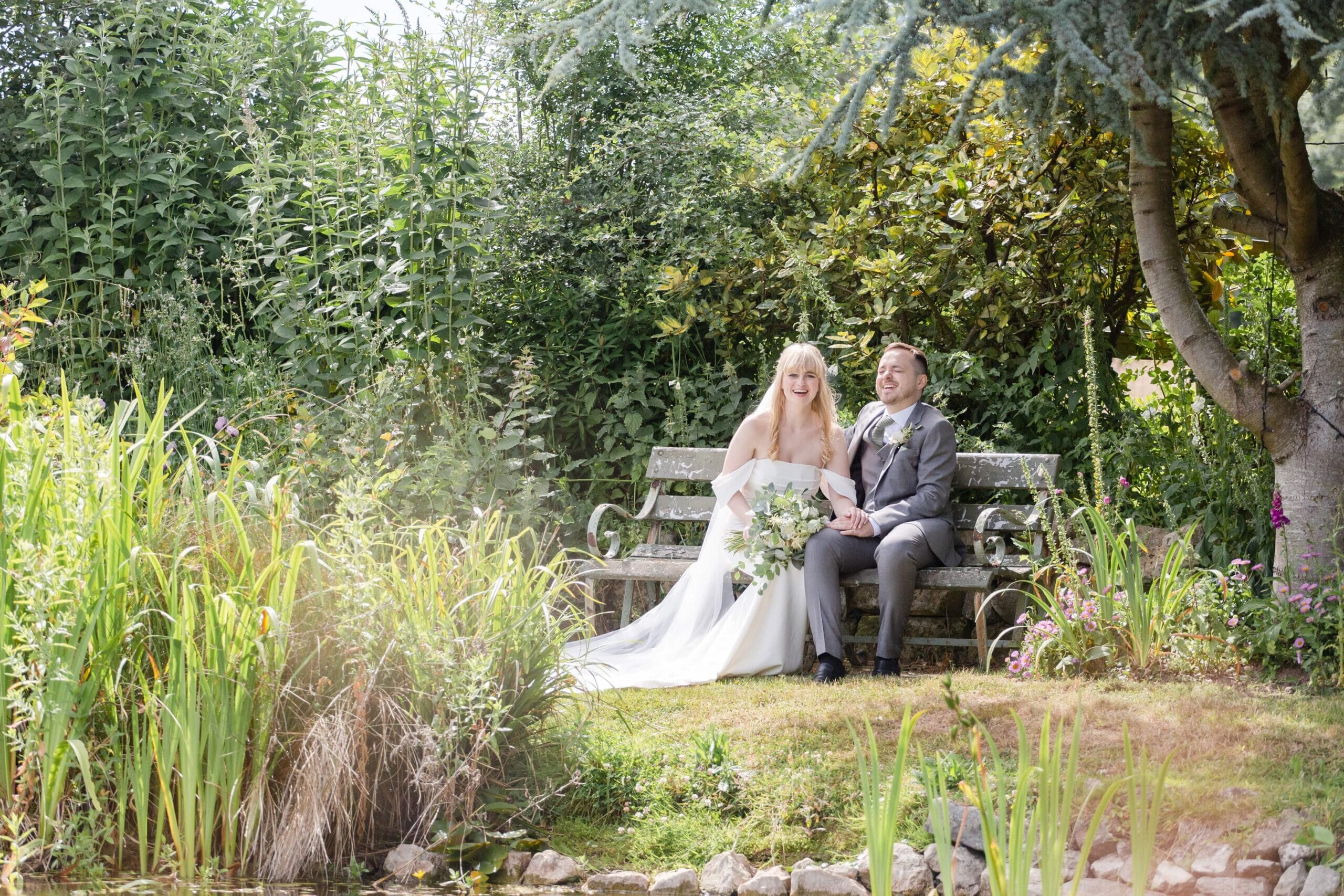 Bride and groom sitting near pond