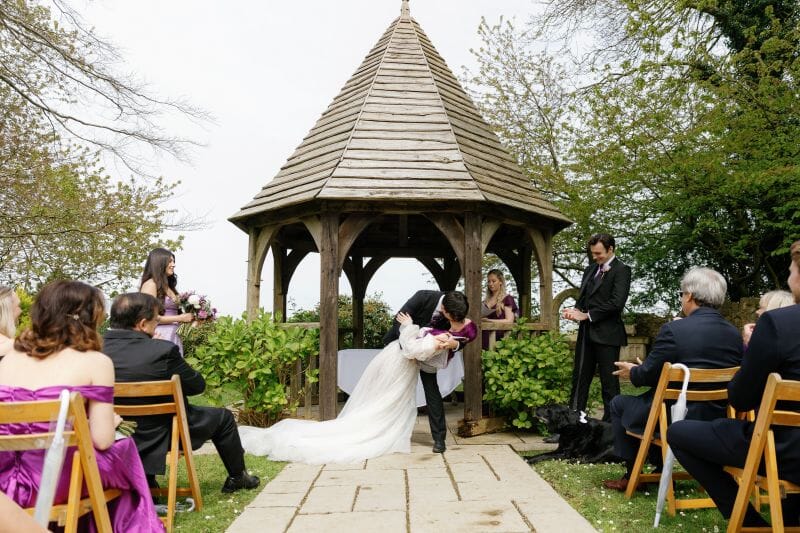 The bride and groom, Kaitlyn and Robbie from America, held their blessing in Godric's Garden with a celebrant at Dover in Kent, here they enjoy a Hollywood style dip kiss in front of their guests