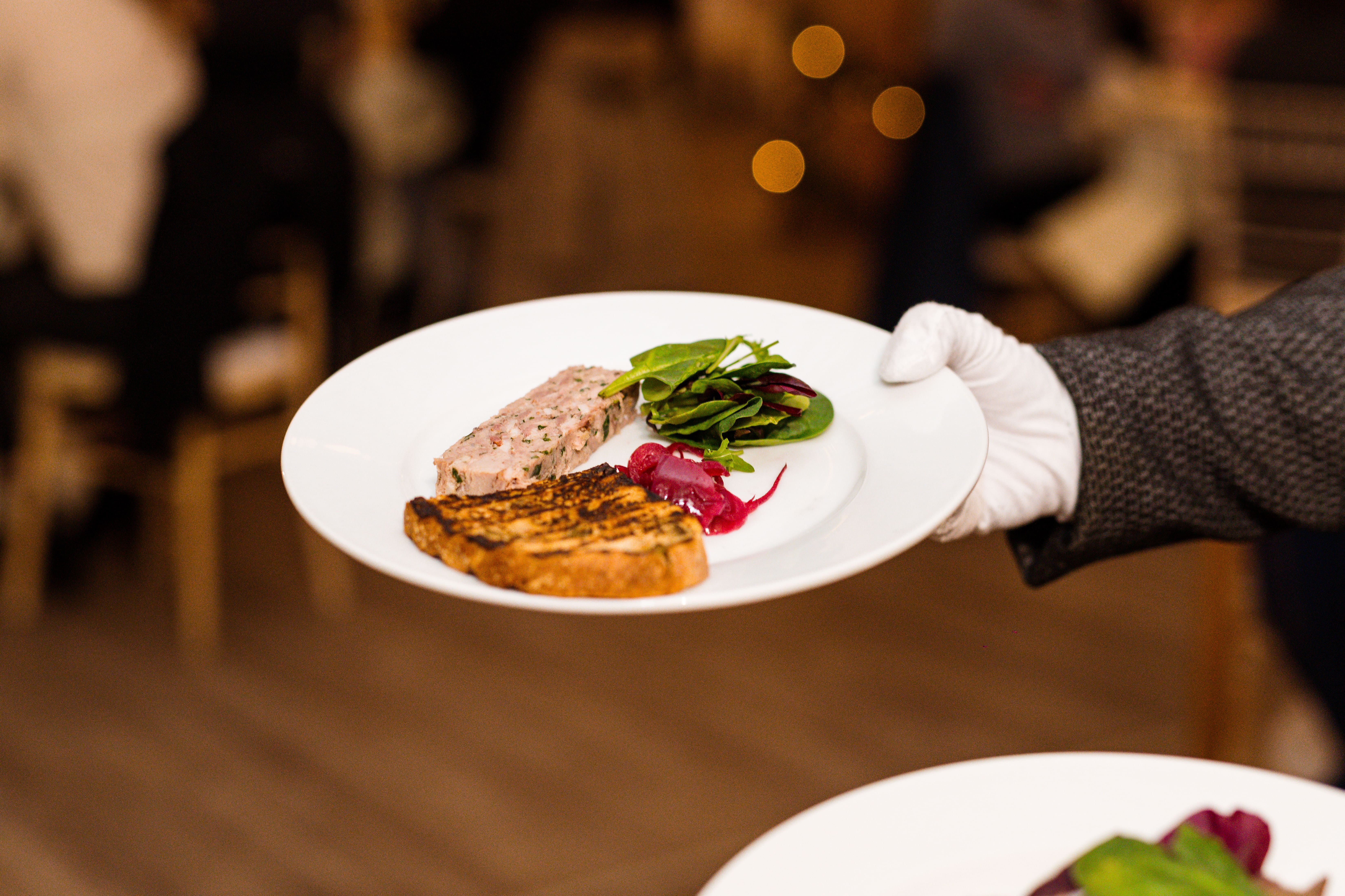 A member of staff holds a plate of pate and toast during a Tasting Evening at Solton Manor, East Langdon, Dover, Kent, England