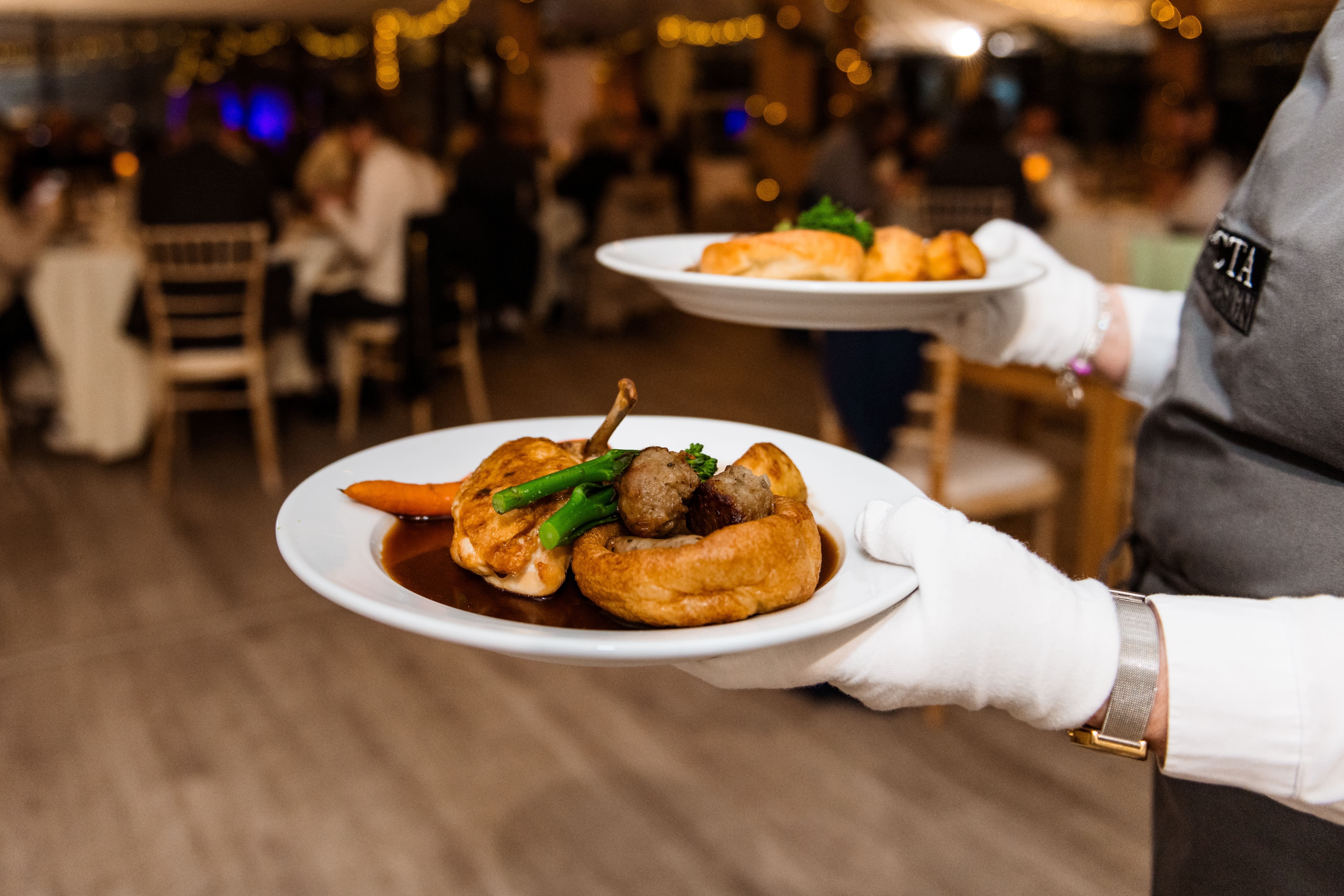 A member of staff holds two plates of roast chicken and Yorkshire Puddings during a Tasting Evening at Solton Manor, East Langdon, Dover, Kent, England