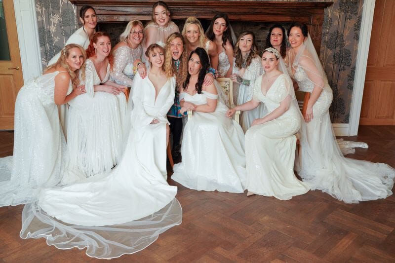 Jeska of Bridal Boutique of Jules stood with lots of brides in the Great Hall of Solton Manor, Dover, Kent, England