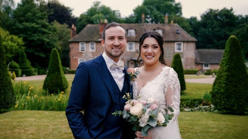 A newly wedding couple stand on the lawns infront of the Solton Manor House, a wedding and events venue near Whitfield, Dover, Kent, England