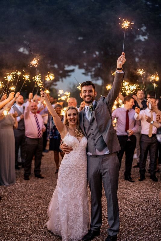 A couple stand in the crescent at Solton Manor and enjoy a sparkler moment with their friends and family during their wedding at one of Kents Best Wedding Venues