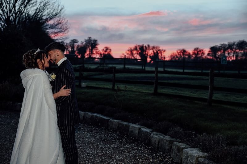 kimberley and Cems after their traditional tea ceremony stand outside the Dutch Barn for this Red Light Sunset at Solton Manor, Kent, England