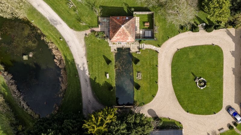 An aerial view of Solton Manor, capturing the Dovecote Cottage, wildlife pond, and front lawn, all part of our licensed wedding spaces.