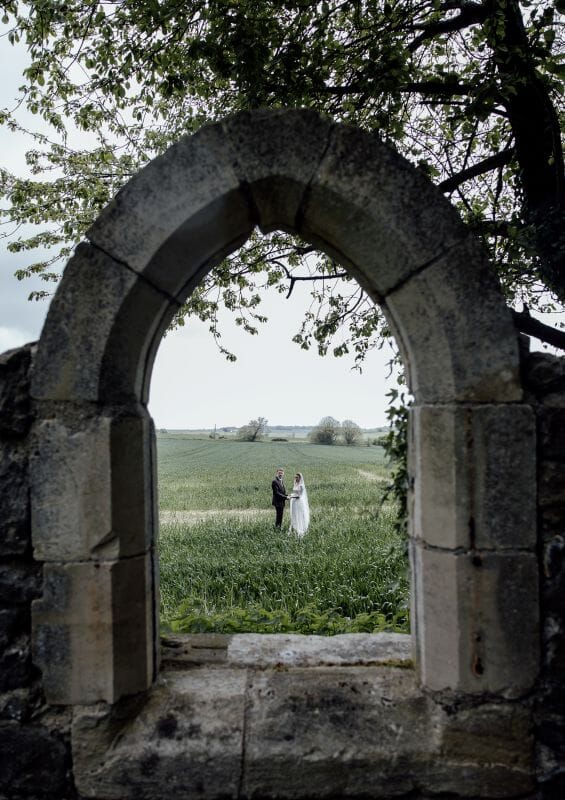 A just married couple stand in the field adjacent to Solton Manor, between Dover and Deal, Kent, England, seen through the ruins