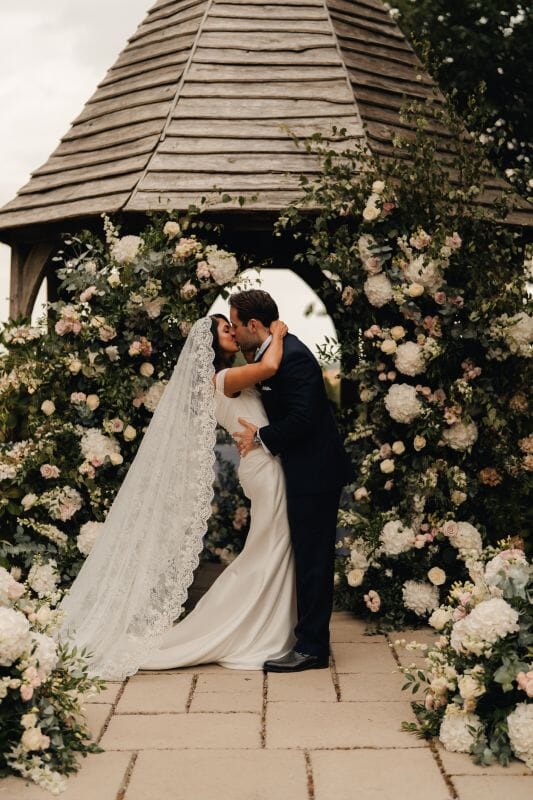Shreya and John, a real bride and groom enjoy a kiss in the outdoor ceremony area, Godric's Garden at Solton Manor, between Dover and Deal, Kent, England